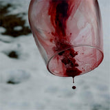 wine glass with blood/wine dripping out and onto the snow below