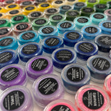 Various rainbows of colors of HoloGrave cosmetics moon water liners (water activated eyeliners) in containers on a table 